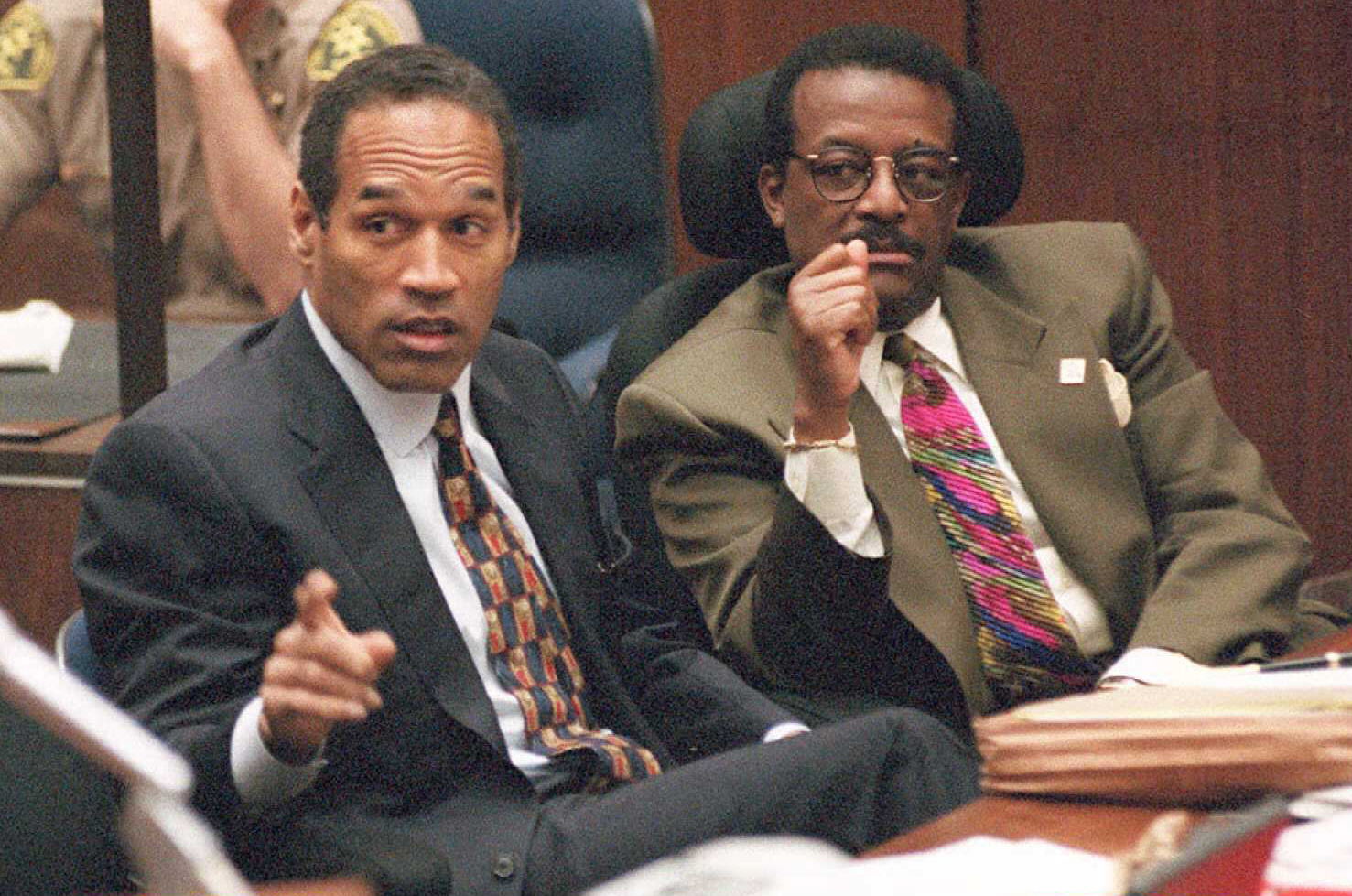 Murder defendant O.J. Simpson (L) points towards p