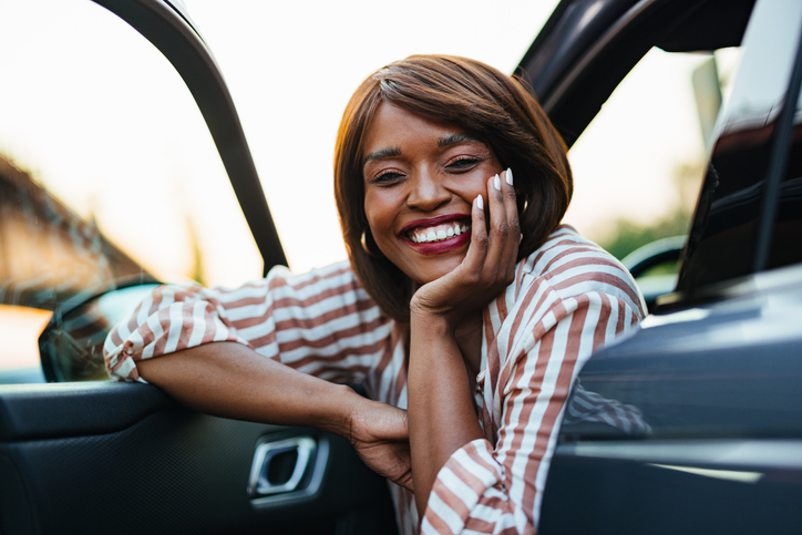 Smiling Businesswoman Enjoys Time in Her Car at Sunset