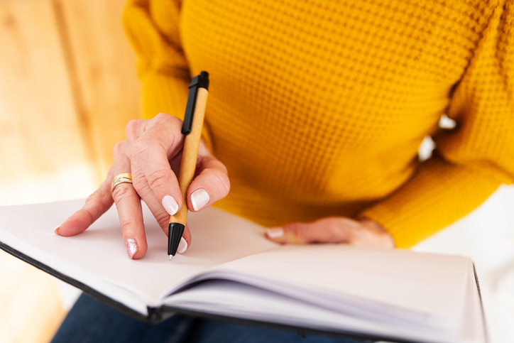 Closeup view of mature woman writing notes in her home office